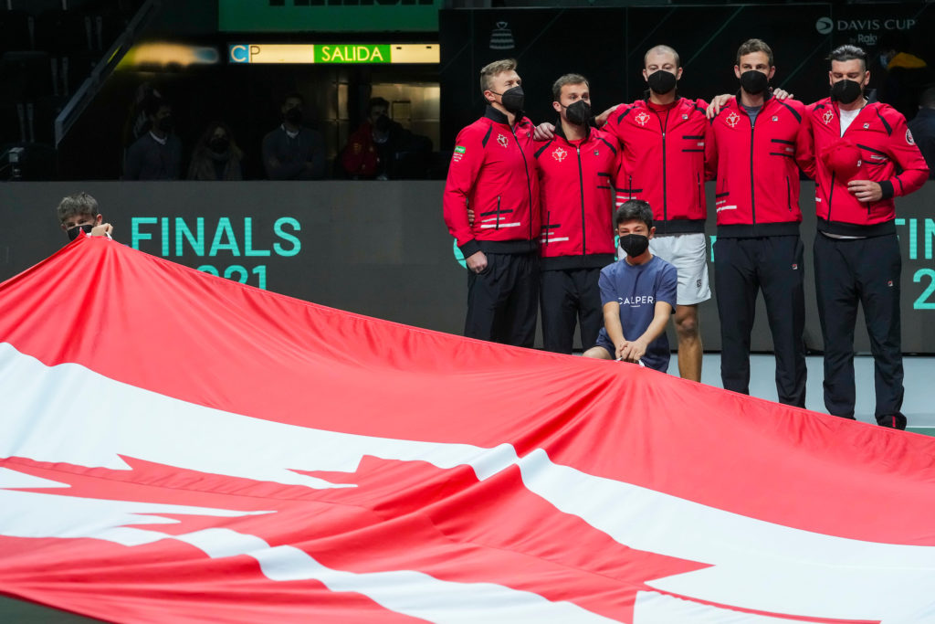 L'équipe canadienne de la Coupe Davis devant le drapeau canadien tenu par les enfants du ballon